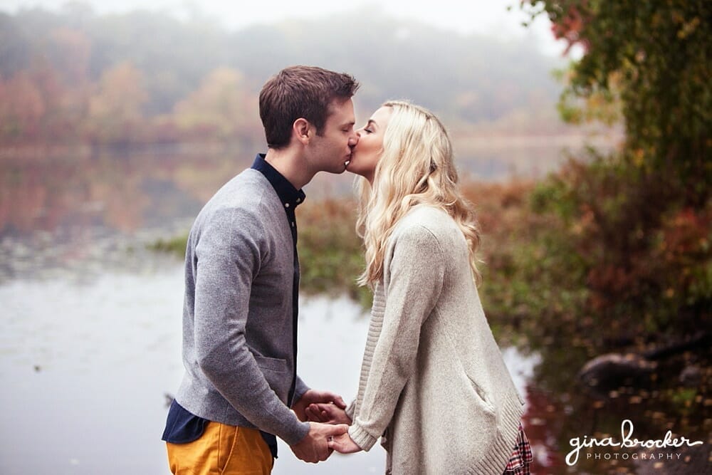 romantic kiss during fall engagement A couple kiss romantically against a misty fall backdrop of the charles river in boston.