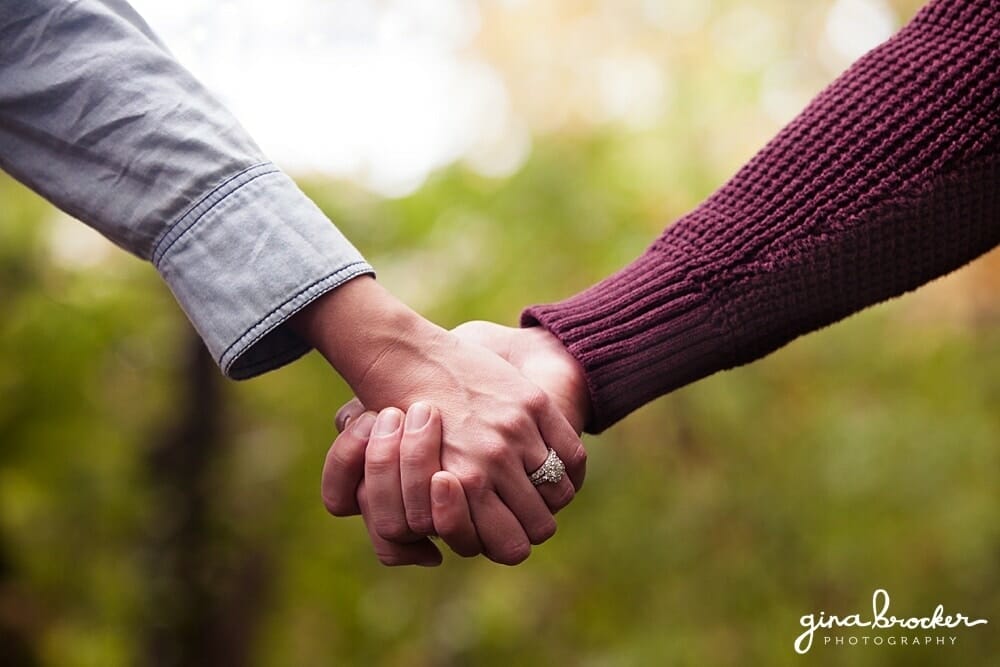 Couple hold hands during engagement A detail of a couple holding hands during their fall engagement session in new england