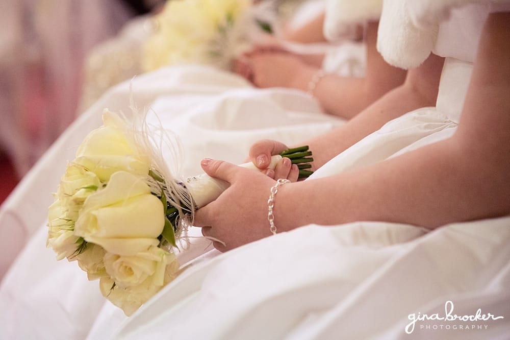 Flower girl holds her white rose bouquet during the classic winter wedding ceremony