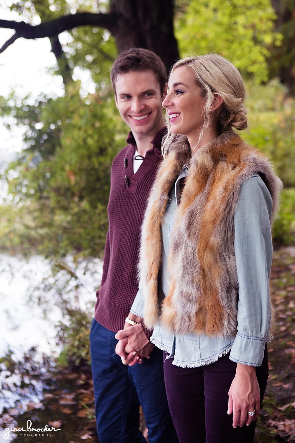 A couple laughs during their sweet autumn engagement session on the charles river in boston massachusetts