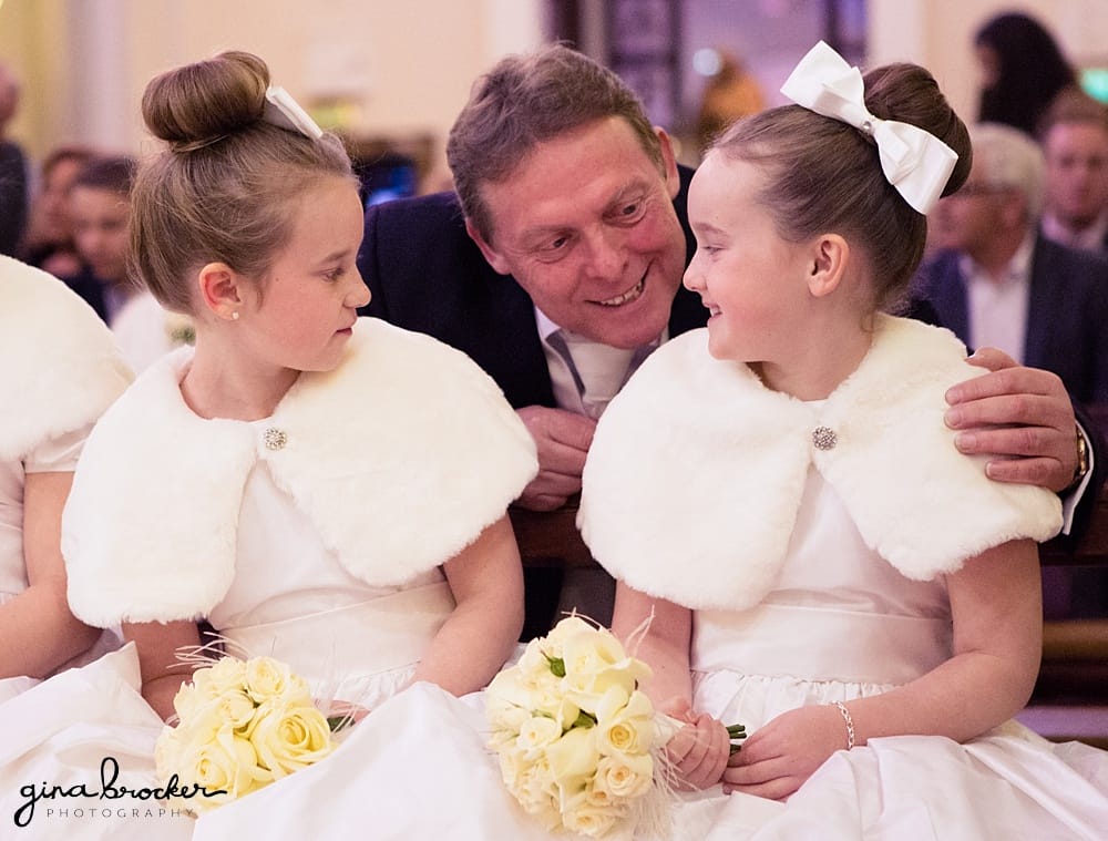 Father of the bride talks to flower girls during the classic winter wedding ceremony