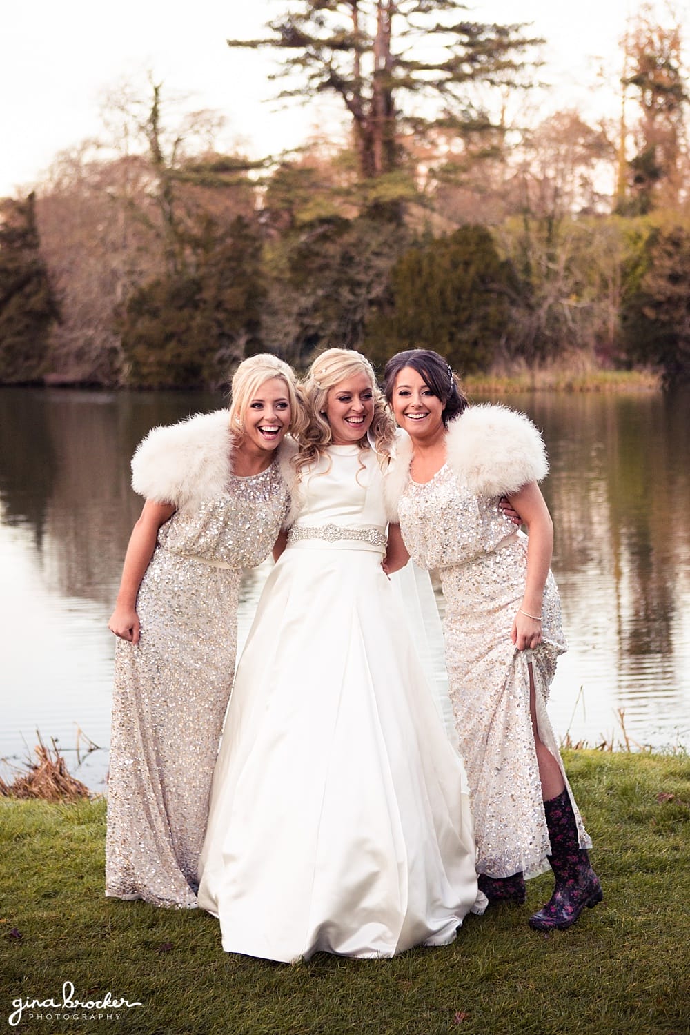 Bride laughs with Bridesmaids wearing silver sparkle dress in front of the lake in the classic winter wedding