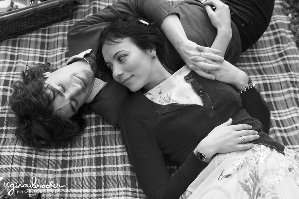 A couple lay together on a blanket during their picnic inspired engagement session in Boston, Massachusetts 