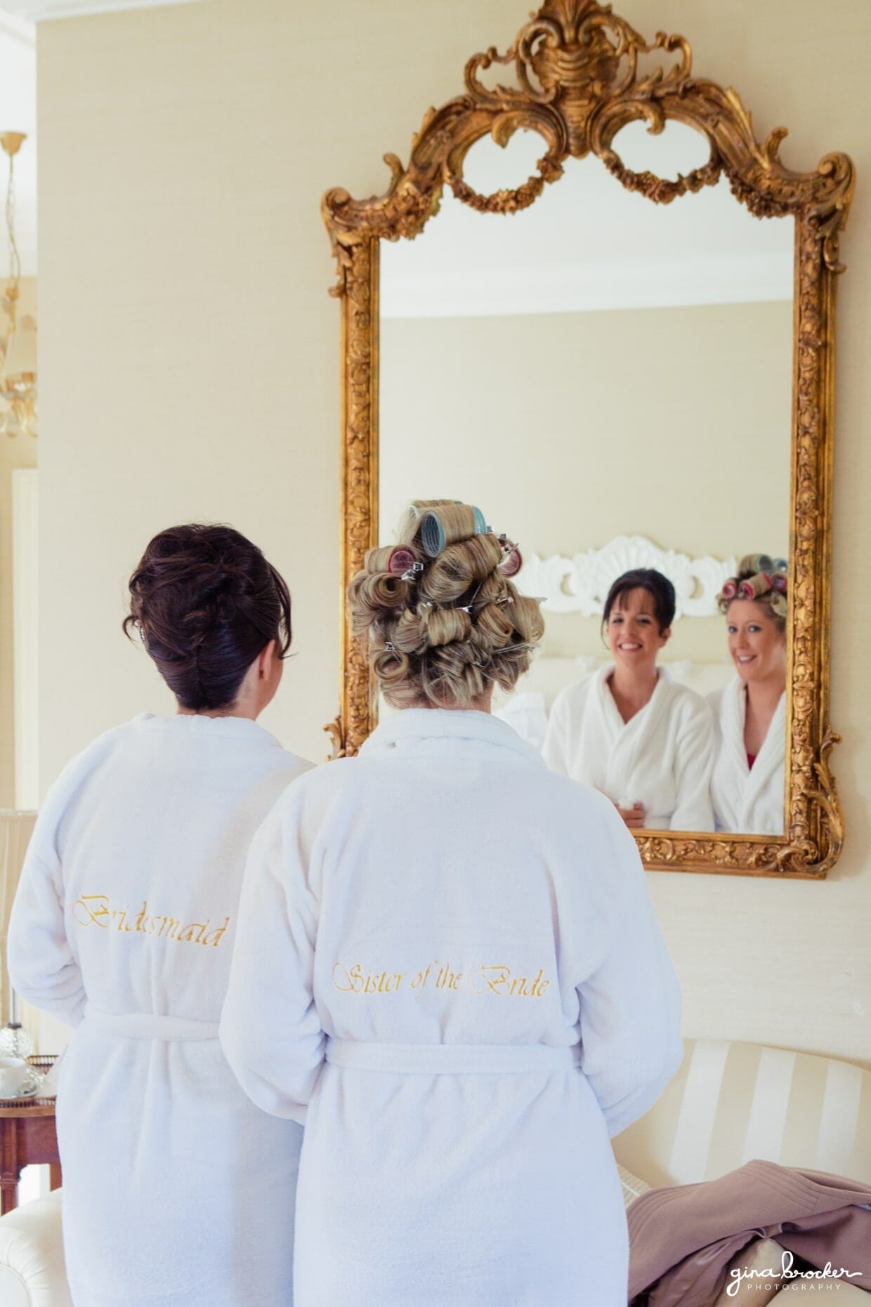 Two bridesmaids look into a vintage and classic mirror on the morning of the wedding