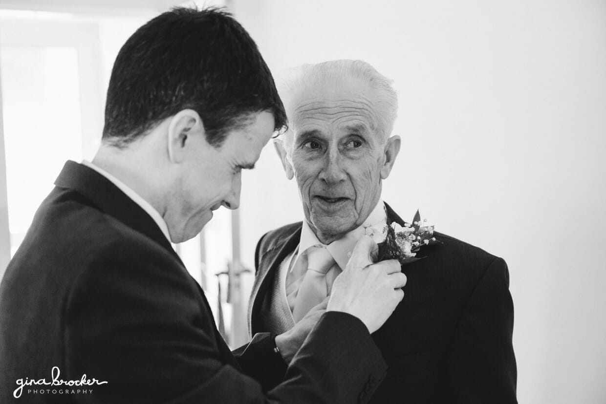 groom-putting-boutonniere-on-father The groom puts a boutonniere on his father during the morning of a vintage inspired wedding