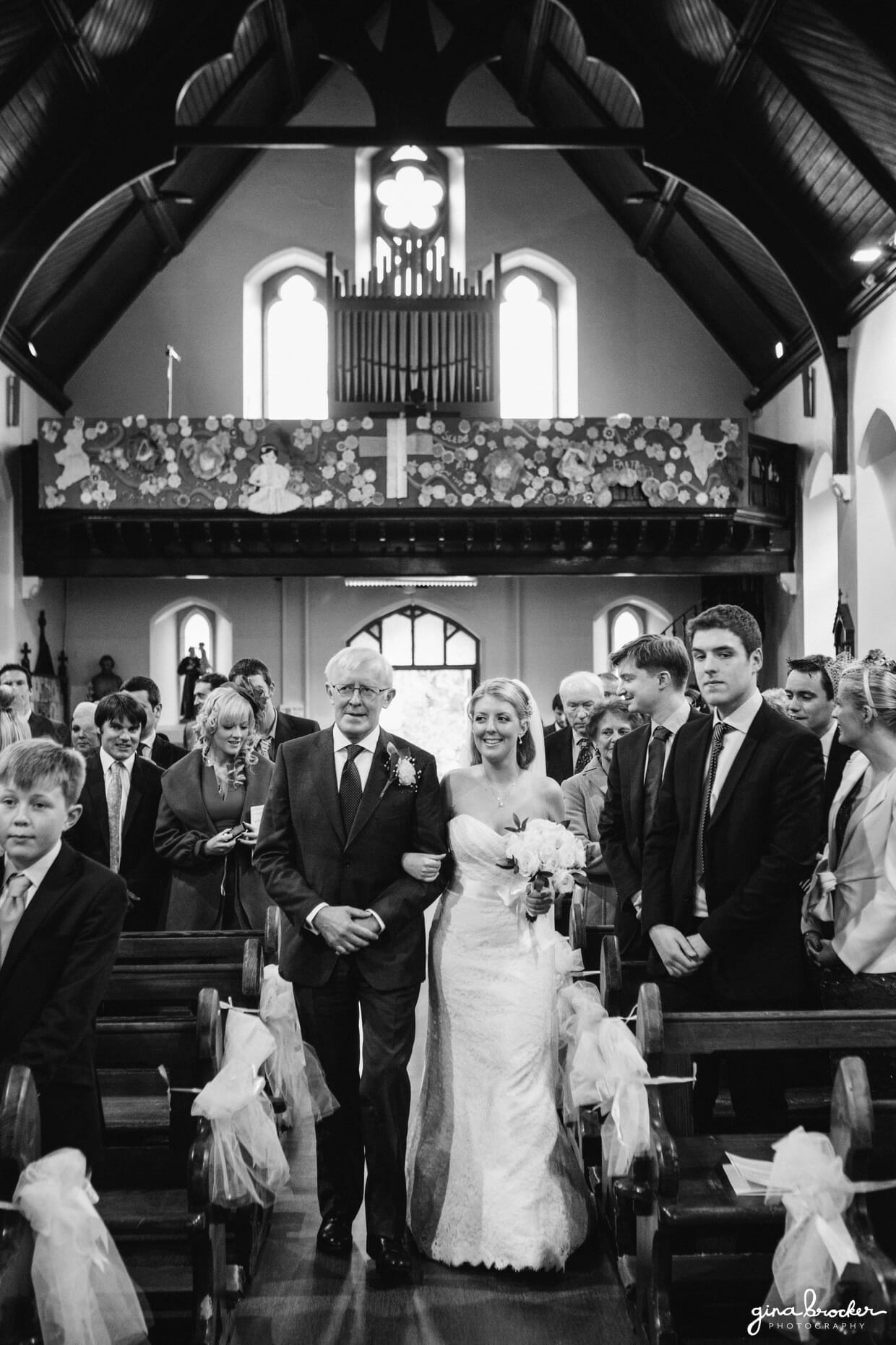 The classic bride walks up the aisle with her father during an intimate church wedding