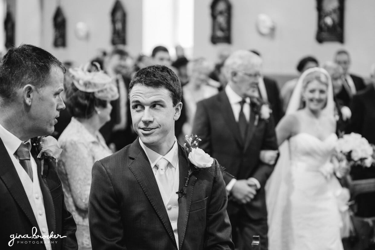 A funny photograph of a groom waiting to look at his bride during their church ceremony in Boston, Massachusetts