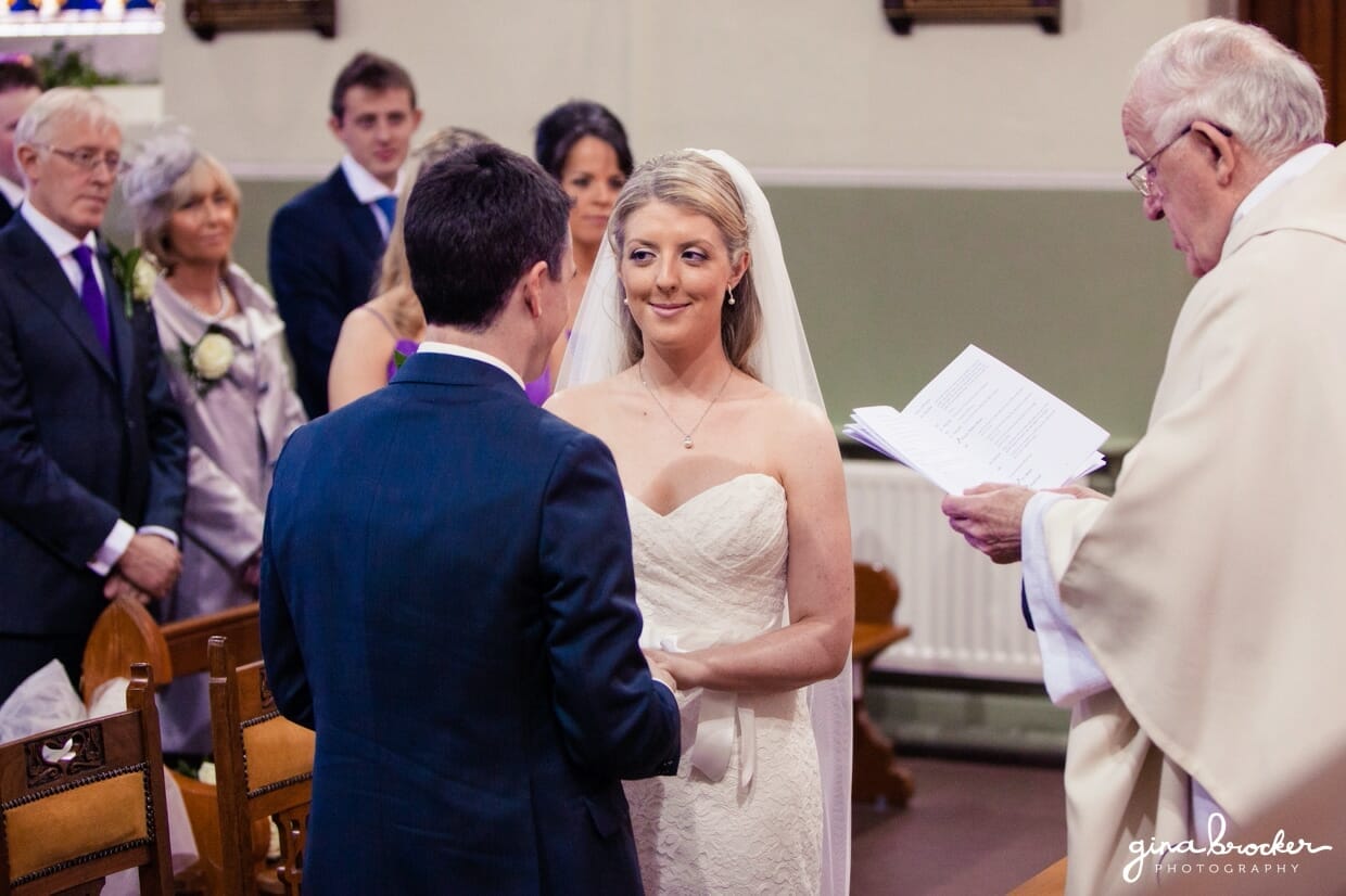 bride-says-her-wedding-vows The bride smiles at her new husband while saying her wedding vows during their intimate catholic ceremony