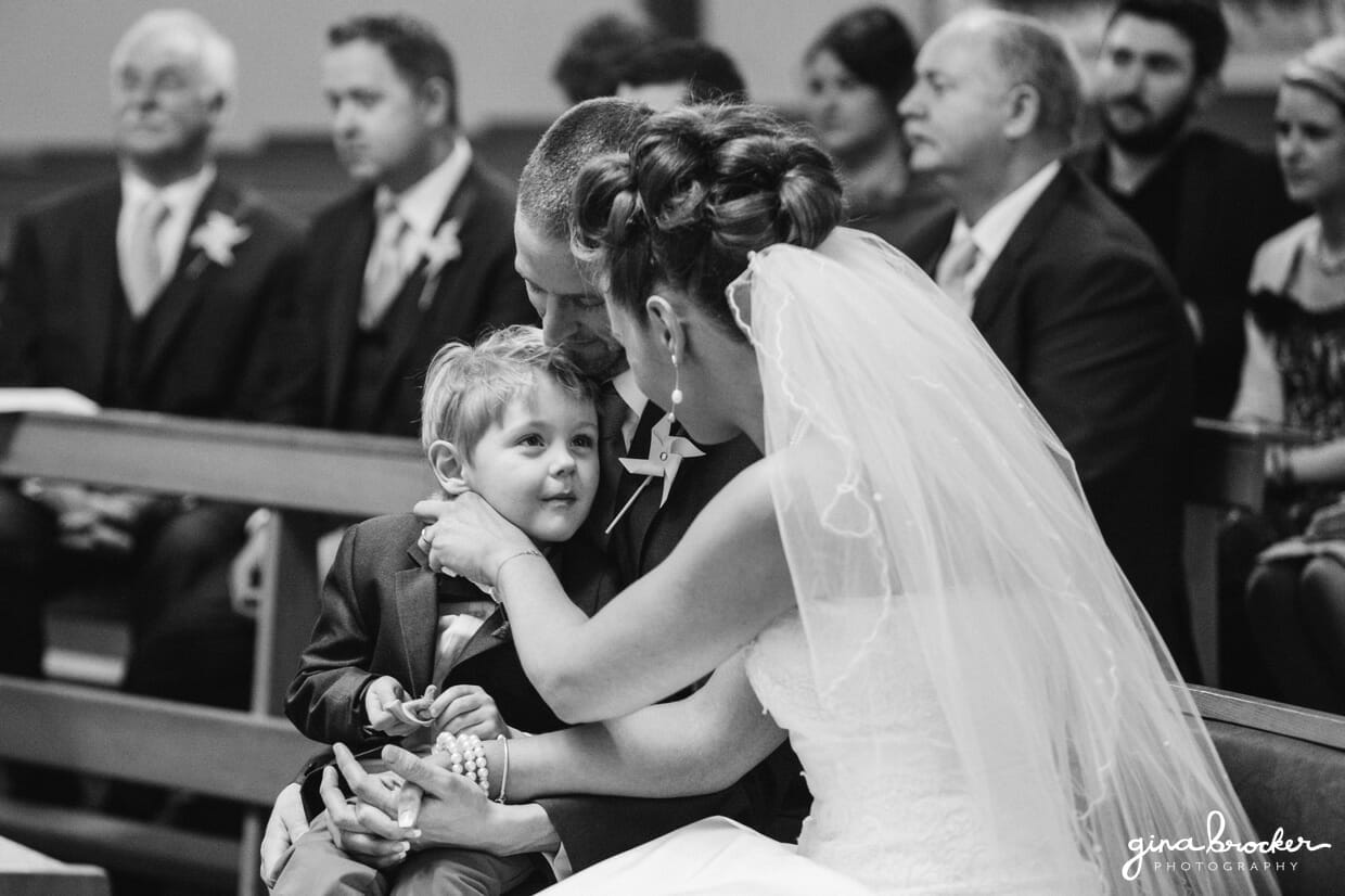 The bride and groom's son sits on their laps during the wedding ceremony