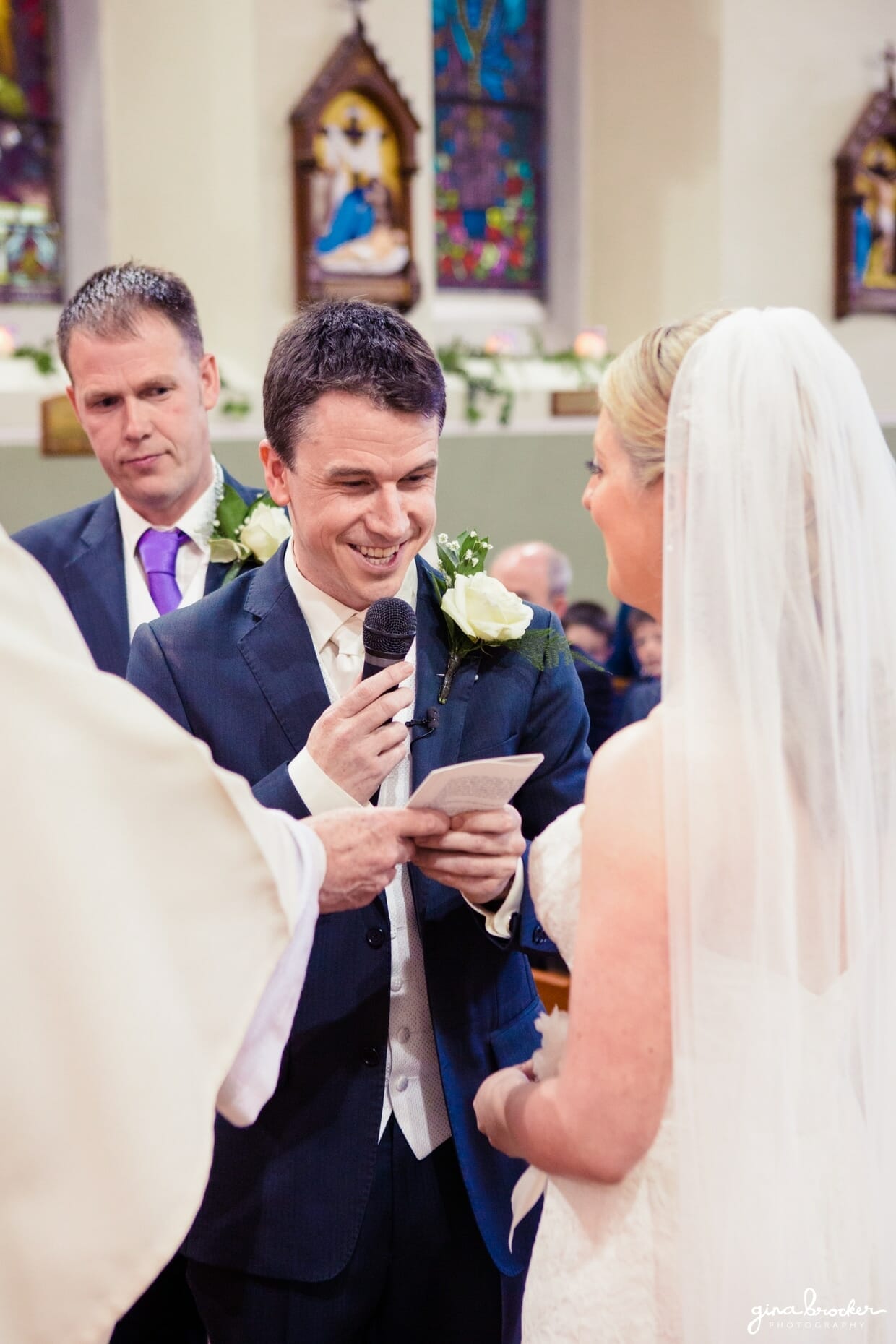 The groom smiles while saying his personal wedding vows to his wife during their religious wedding ceremony in a quaint church