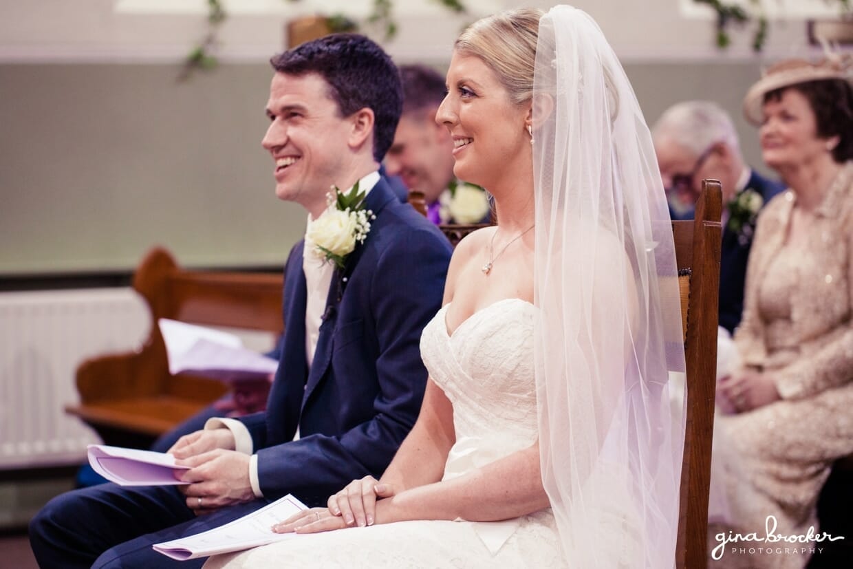 classic-vintage-wedding-ceremony The bride and groom smile as one of their friends reads a personal message at their intimate church wedding