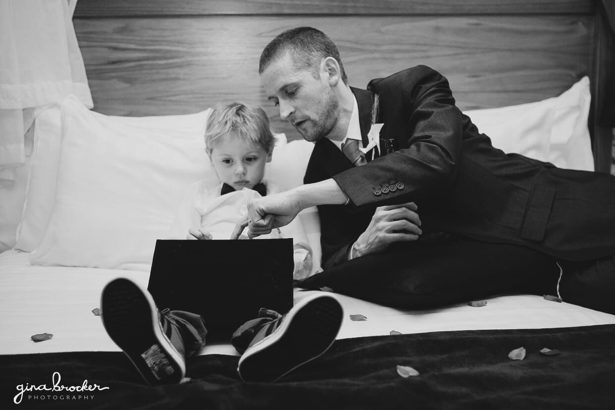 The groom spends a few moments playing games with his son on the ipad during his fun wedding