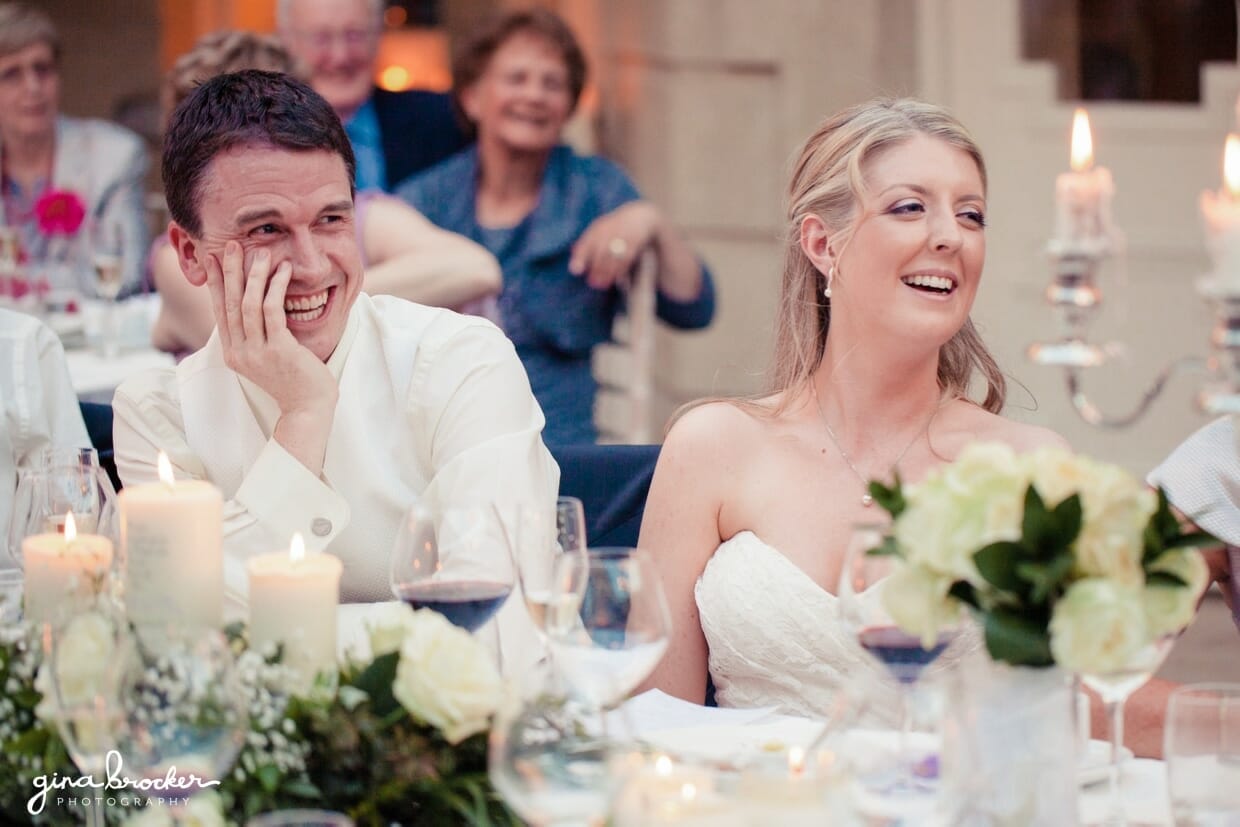 A bride and groom laugh during the best man speech at their classic new england wedding outside of Boston, Massachusetts