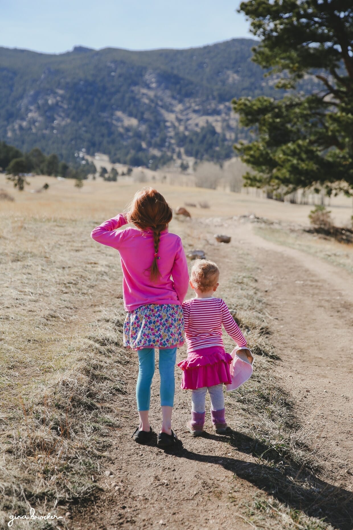 01.children.playing.in.nature A candid photograph of a child holding her sisters hand as they look up at the mountains