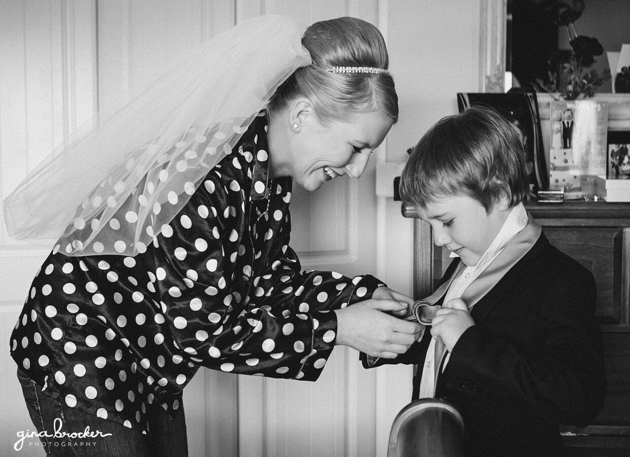 A bride smiles as she helps her son put on his necktie before her sweet vintage wedding