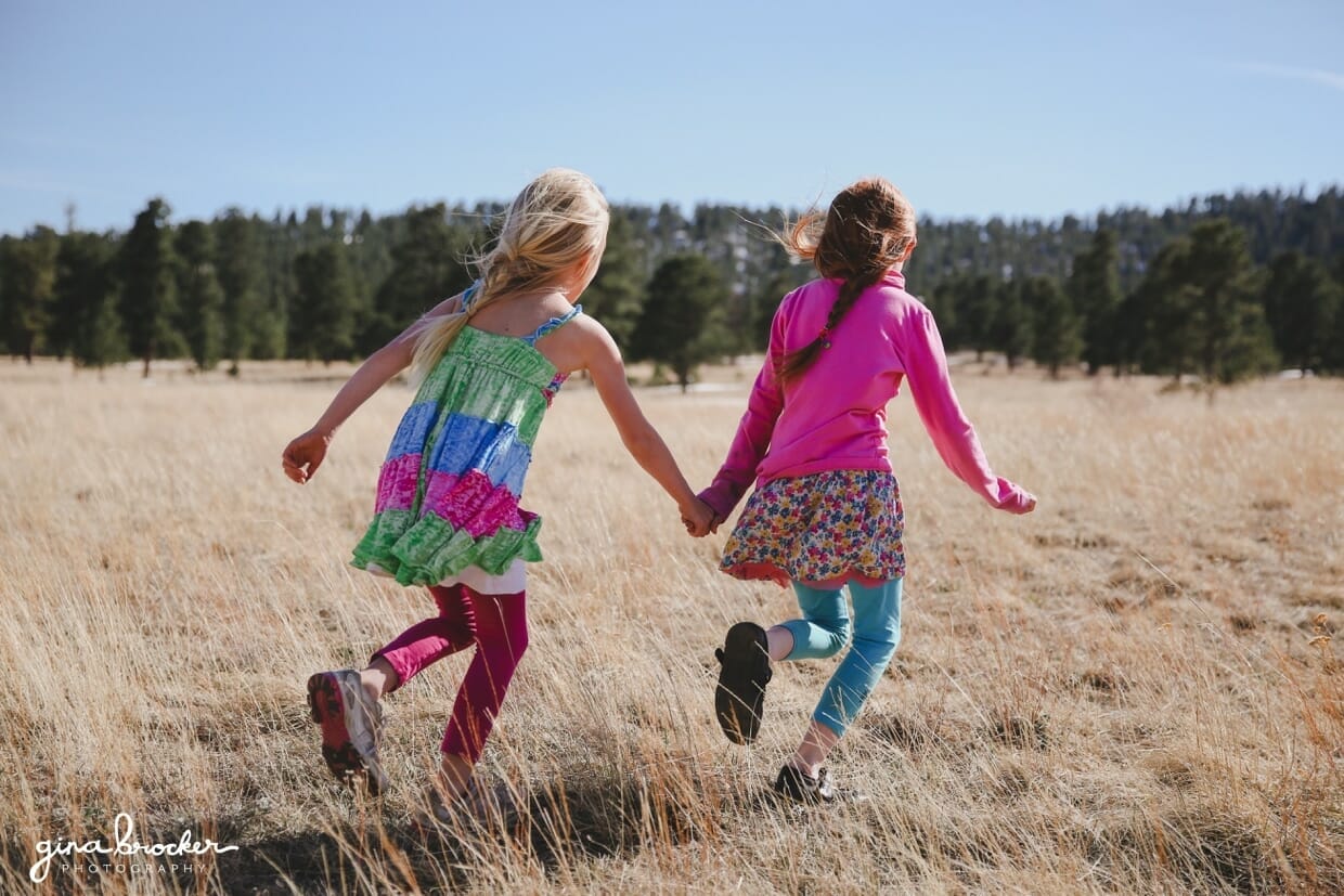 03.sisters.running.in.field Two sisters hold hands as the run into the field during their outdoor photography session