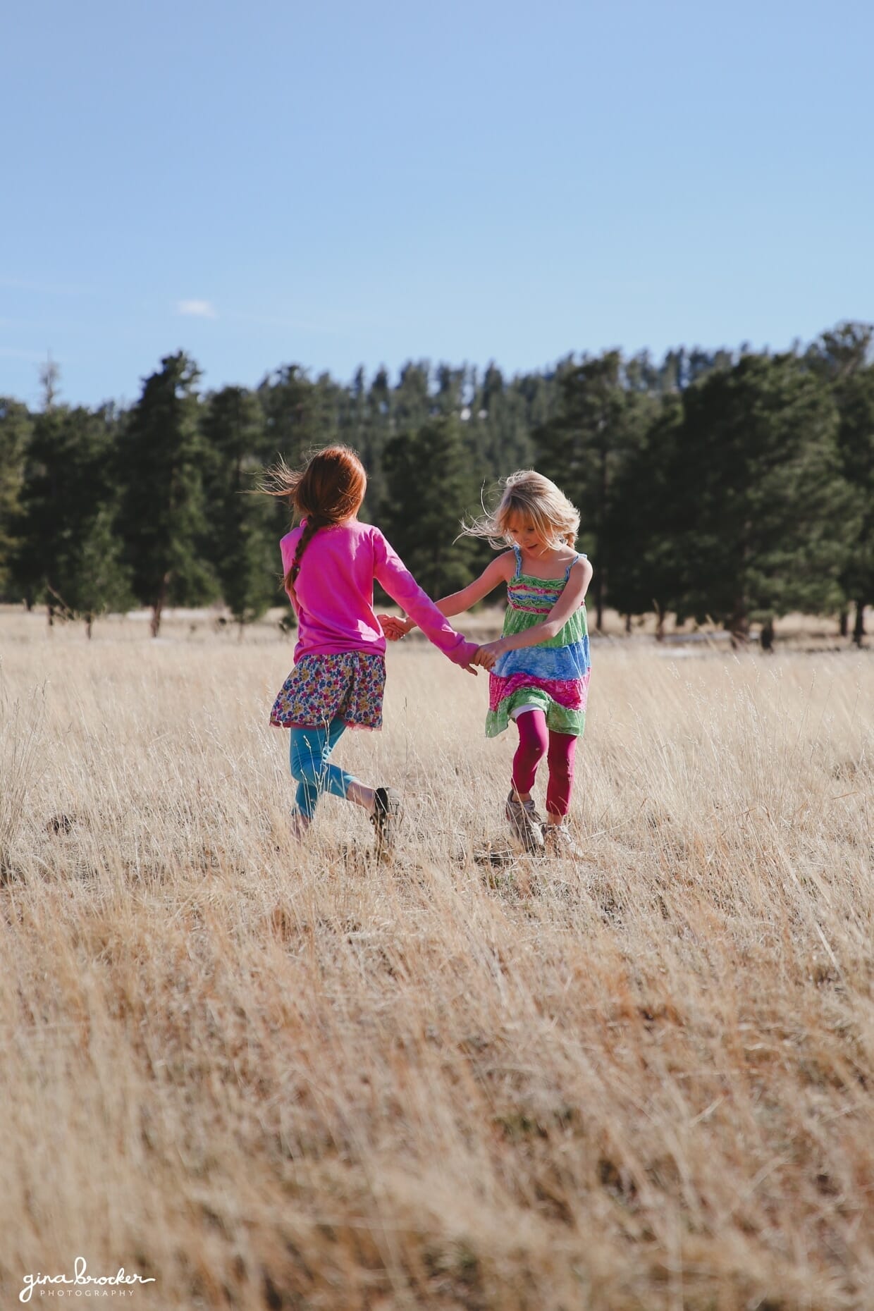 Two kids dance around in a beautiful field during their outdoor family photo session