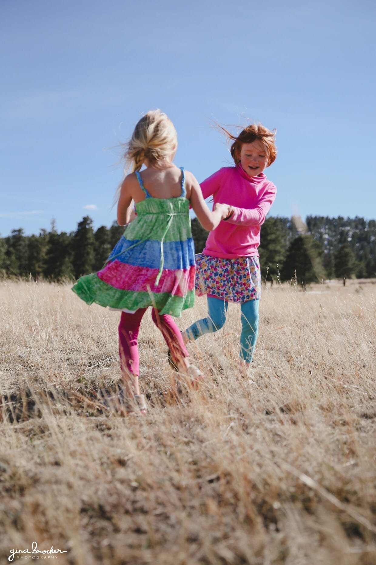 Little girls spin around in a field during their family photo shoot