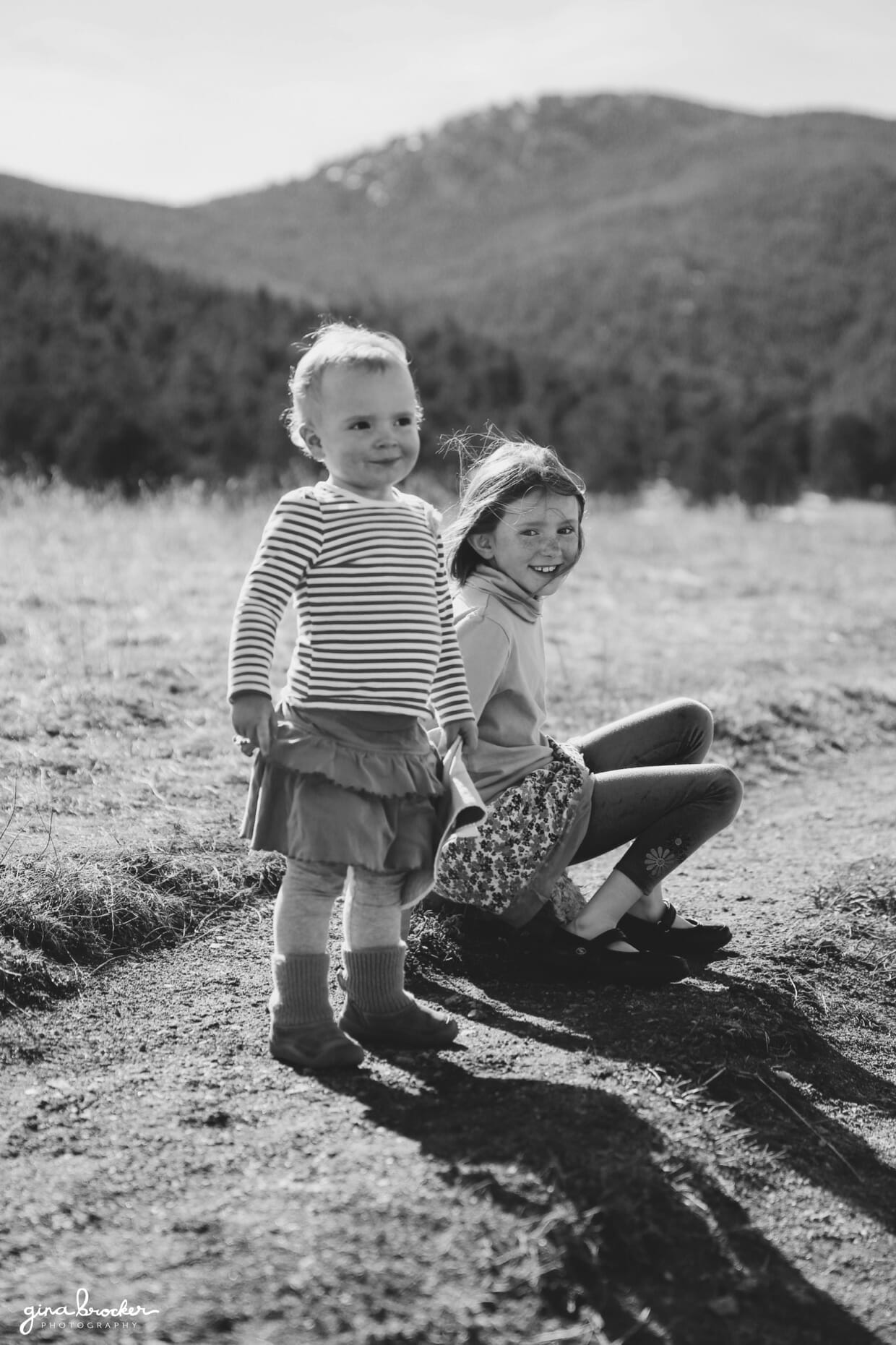 portrait of a young girl and toddler in a field