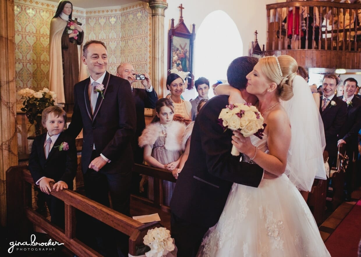 The groom hugs as bride as she arrives at the top of aisle for their intimate wedding ceremony