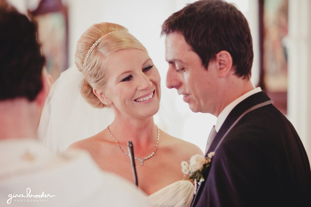 The bride smiles at the groom while he says his sweet wedding vows during their intimate church wedding