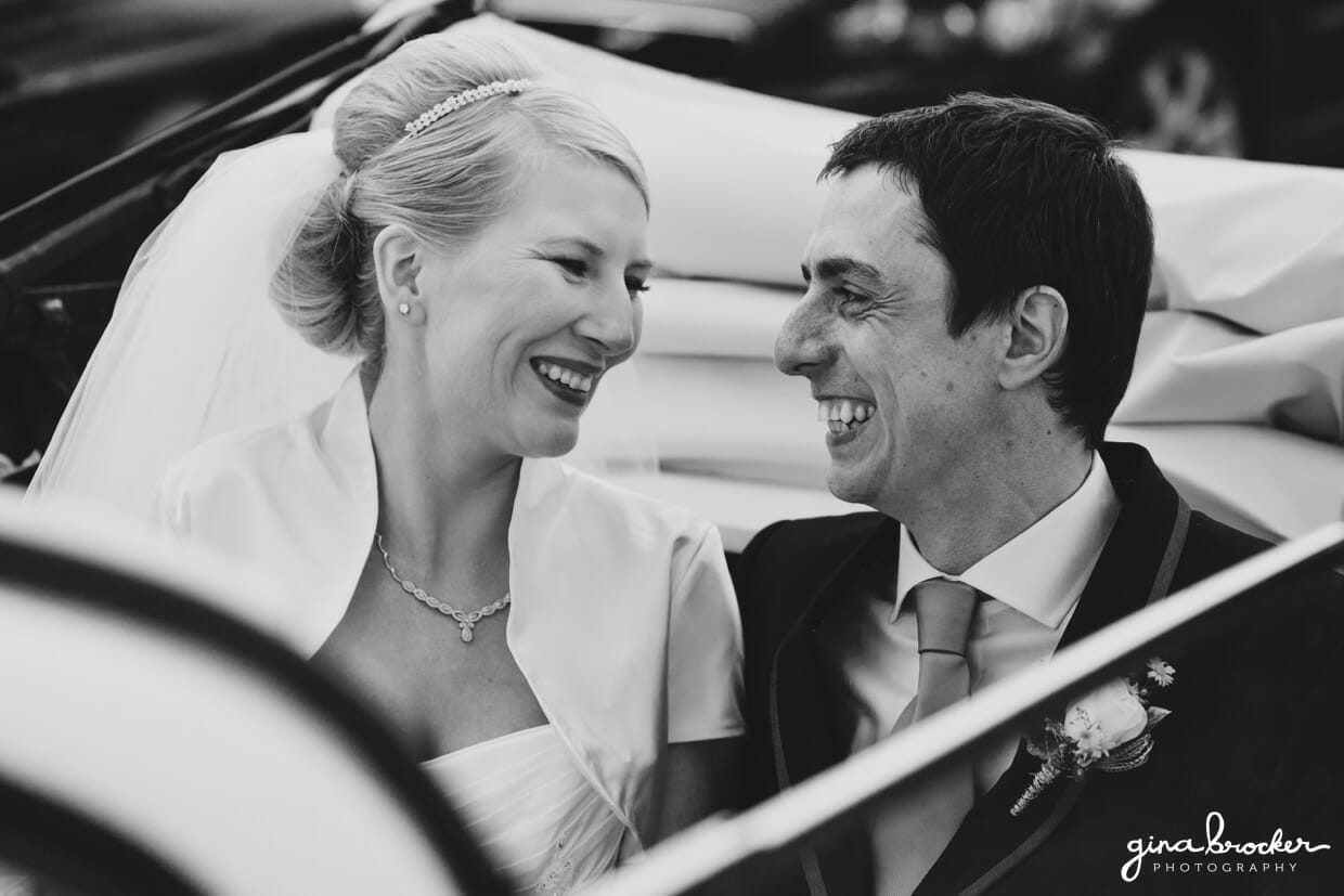 The bride and groom look lovingly at one another as they drive off in their vintage vw bug after their wedding ceremony