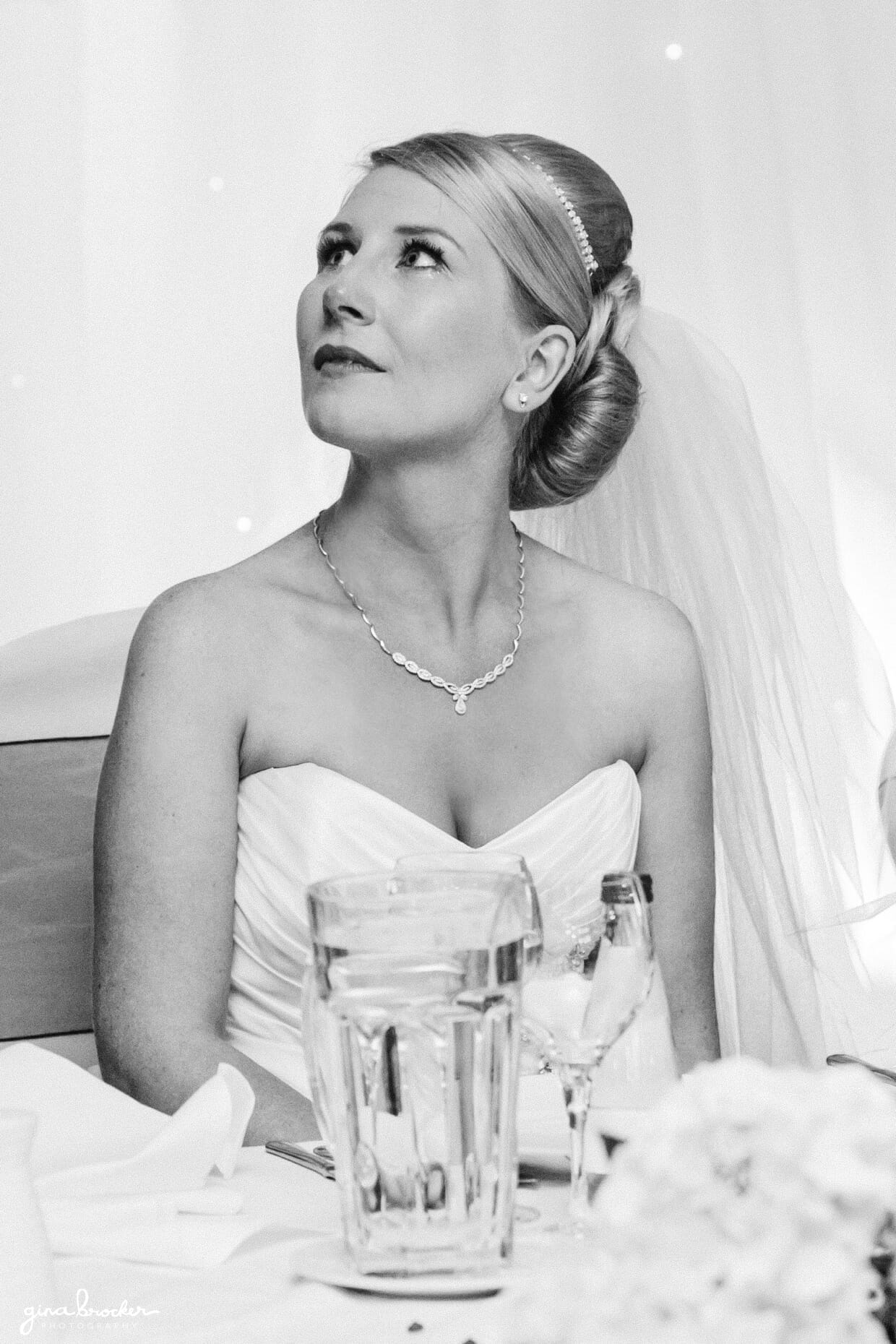 The bride looks at the groom with tears in her eyes during his sweet and touching wedding toast