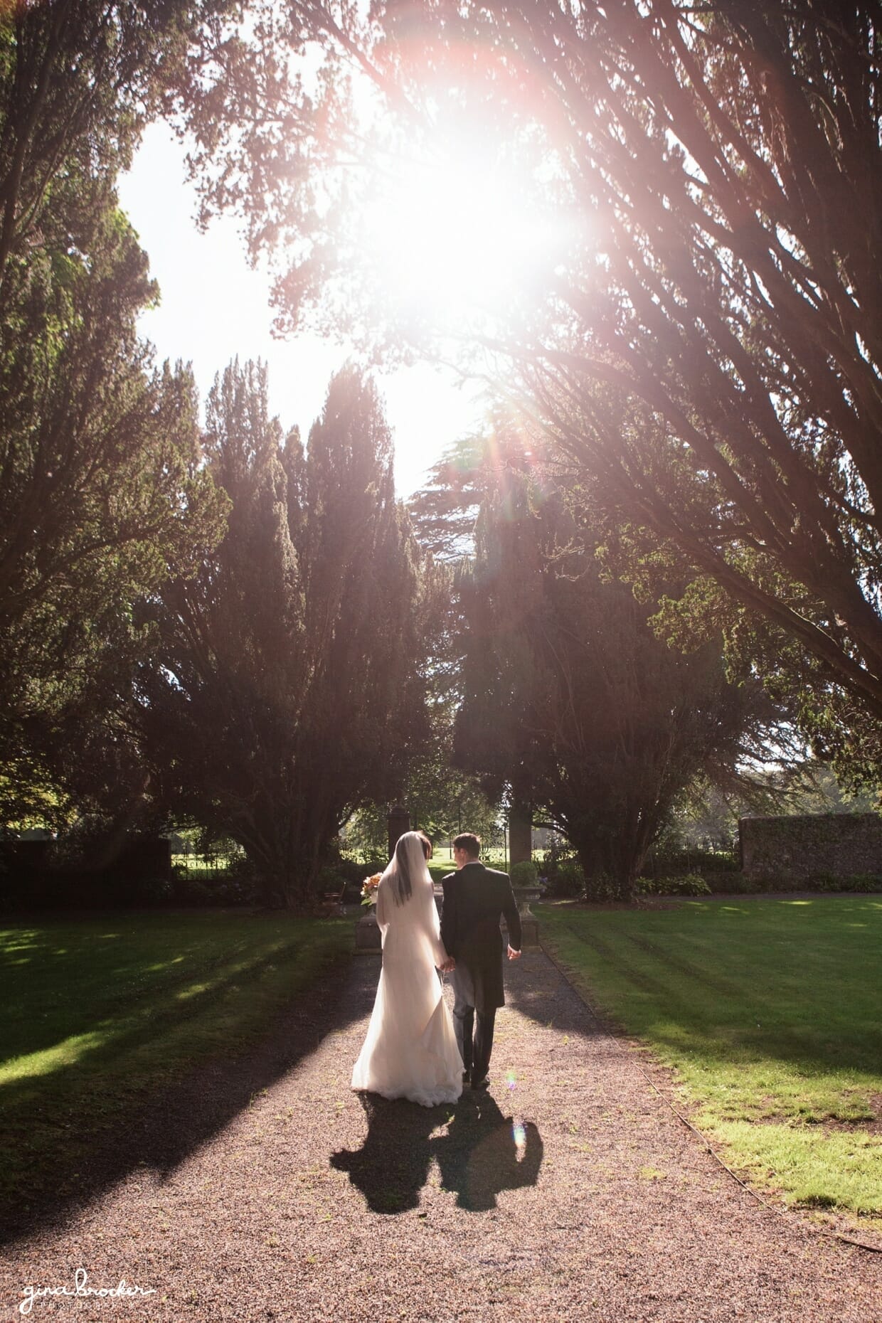 A beautifully lit wedding portrait of the bride and groom walking away in the sunset