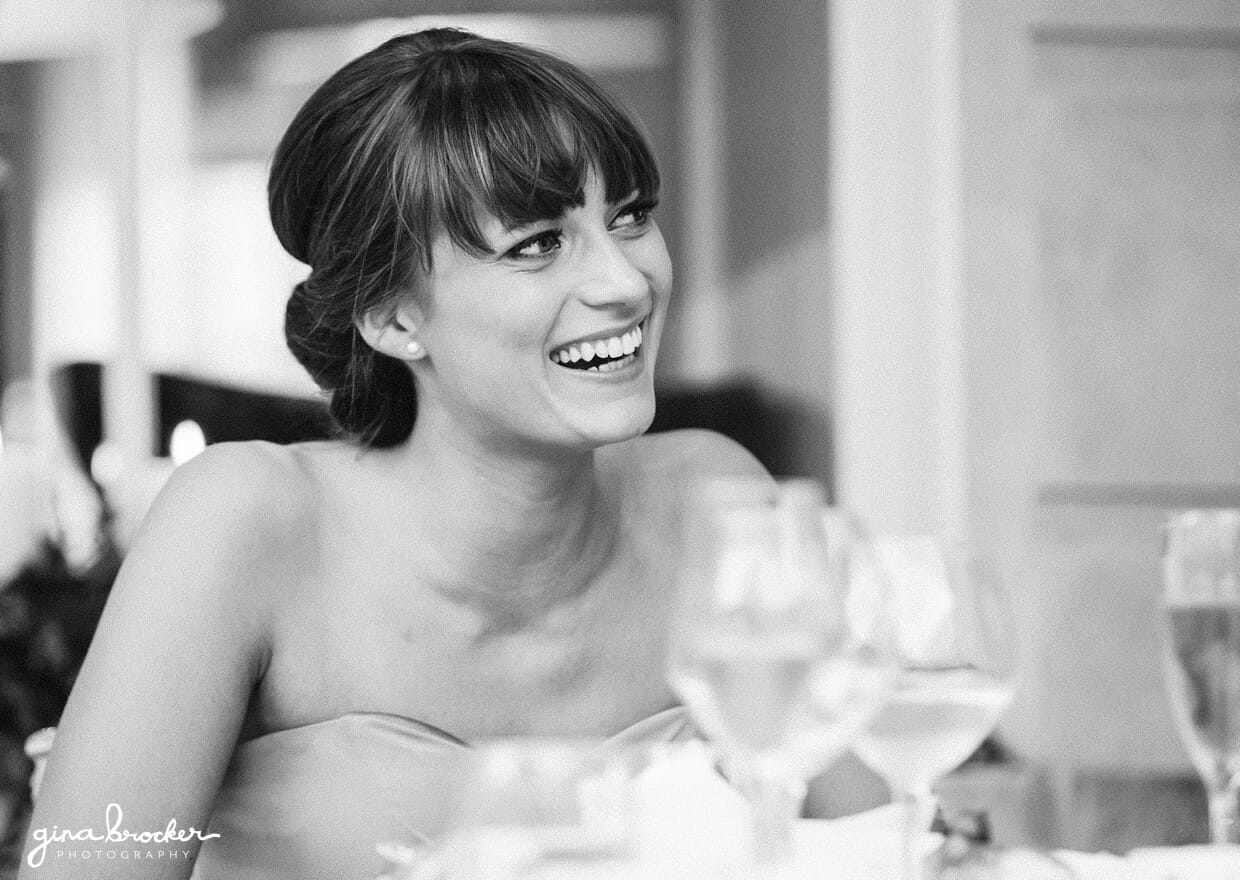A candid portrait of a bridesmaid laughing during the wedding speeches