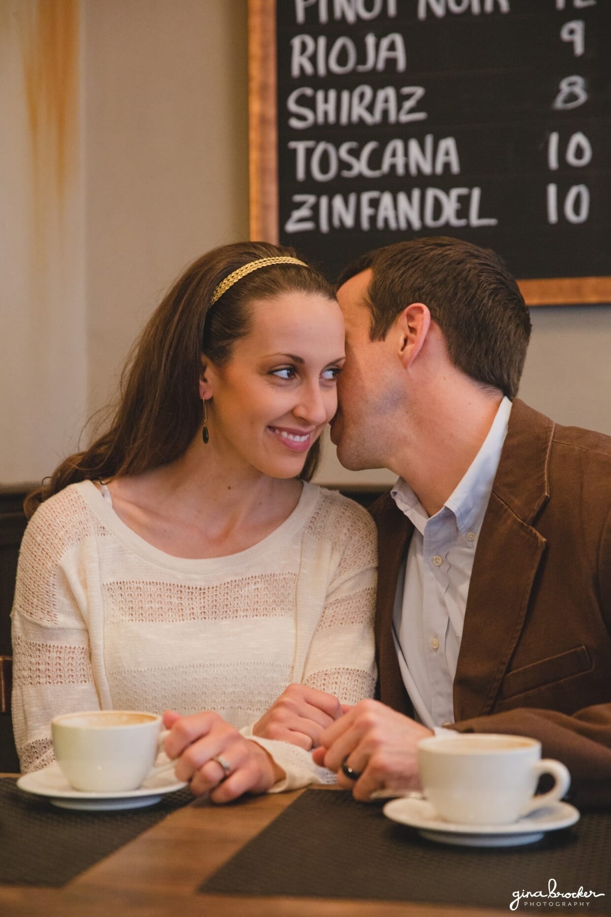 A husband whispers something into his wife's ear during their sweet beacon hill couple session in a boston cafe