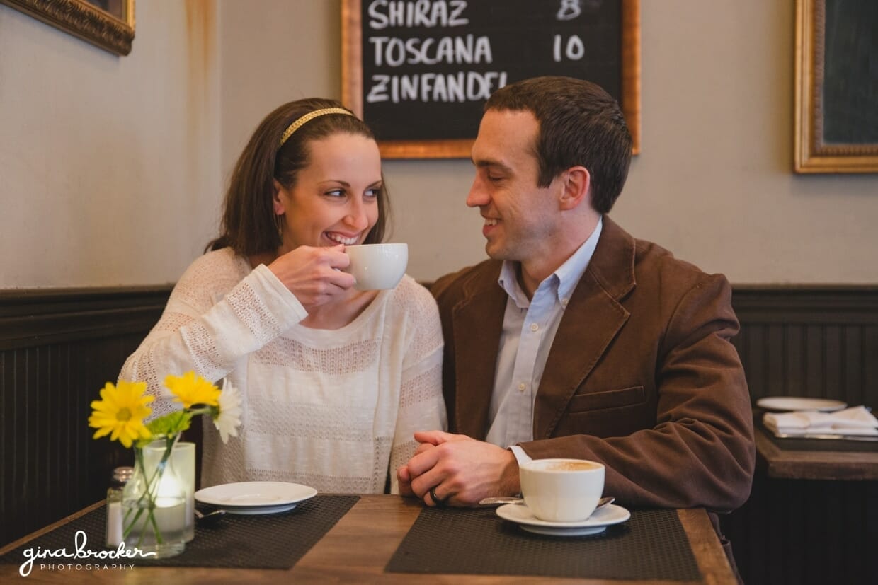 A couple laugh together during their relaxed and unique couple session in a boston cafe