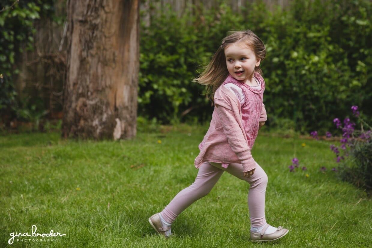 A toddler running in her yard during a family photo session in their Boston home