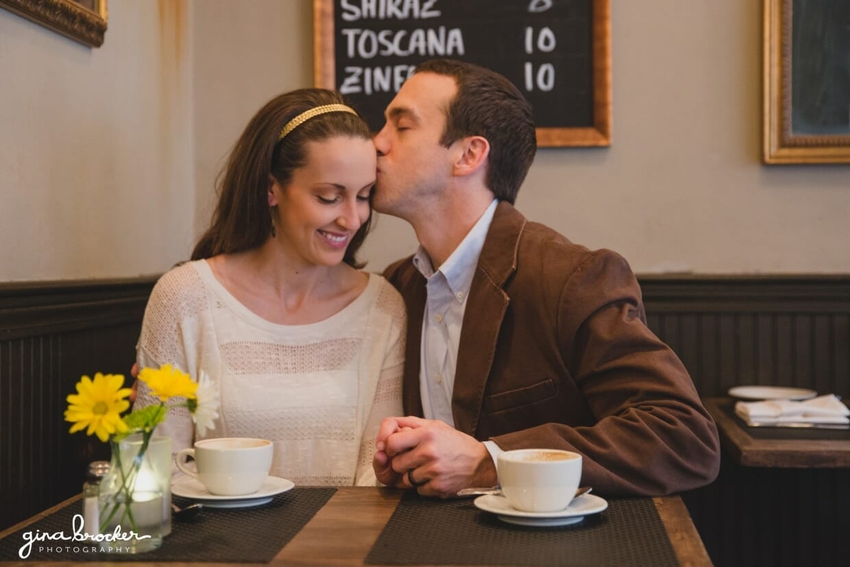 A husband kisses his wife's cheek during a relaxed and sweet beacon hill couple session in a boston cafe