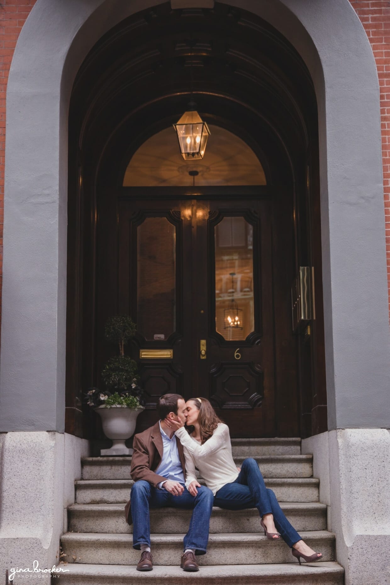 A sweet portrait of a couple kissing as they sit on the steps of their Beacon Hill home during a Boston engagement session
