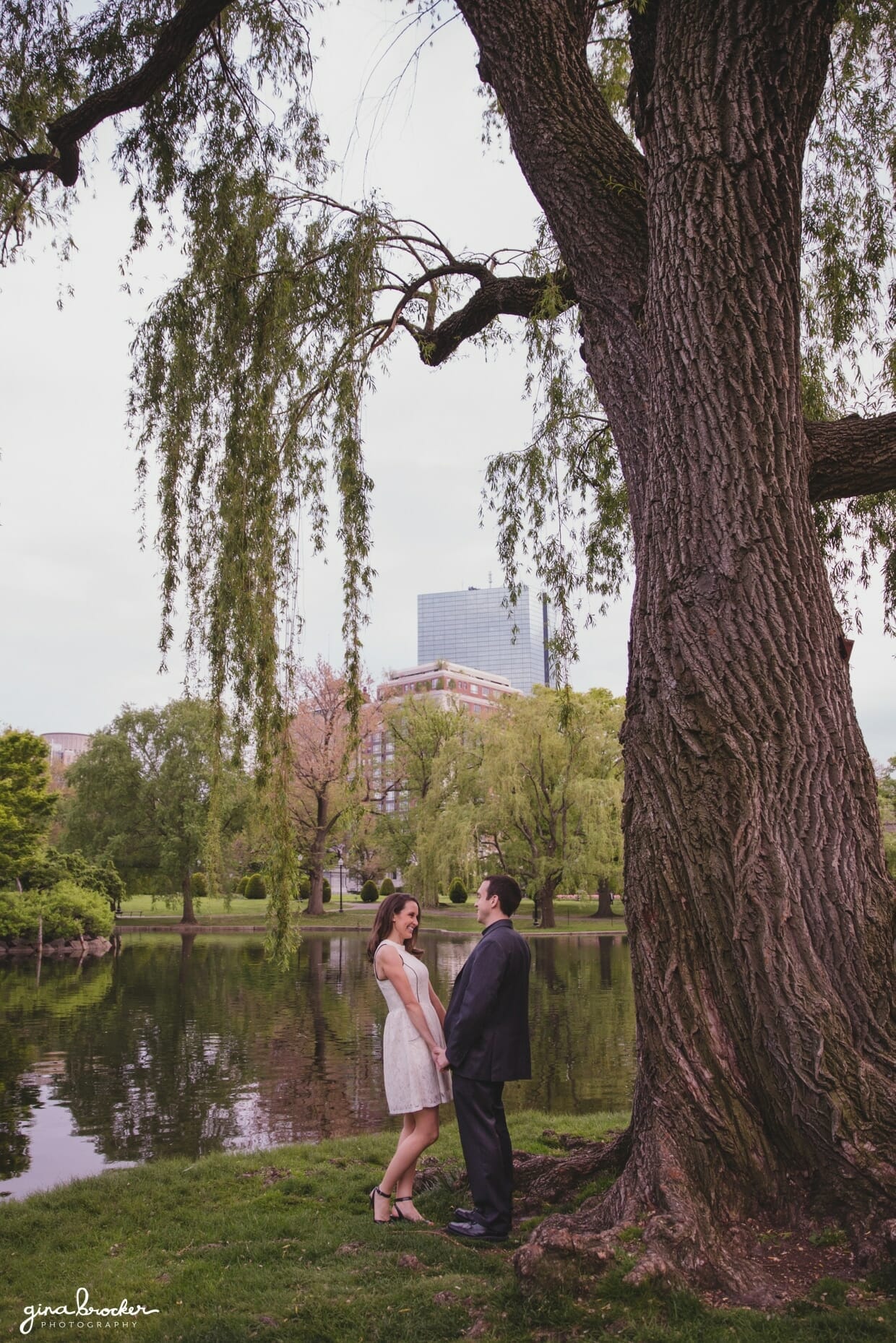 A couple laugh together during their sweet engagement session in the Boston Public Gardens