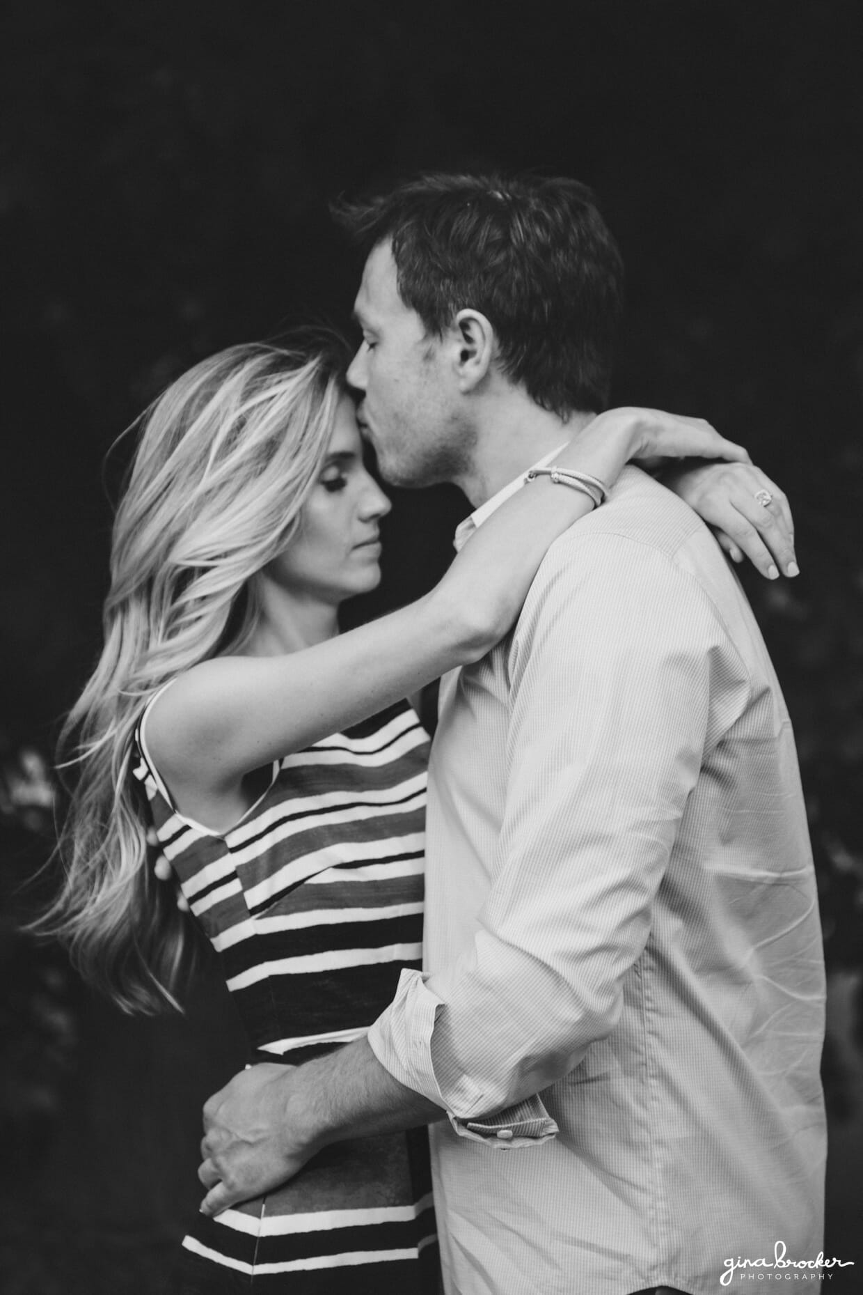 A romantic portrait of a couple as a man kisses his fiancee's forehead during their prospect park engagement session in brooklyn, new york