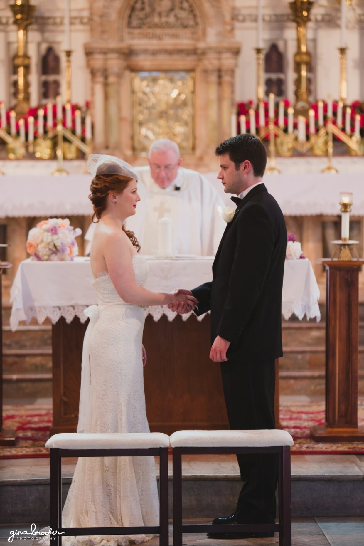 A bride and groom hold hands as the make their wedding vows during their wedding ceremony at the Sacred Heart of Jesus Church in Cambridge, Massachusetts