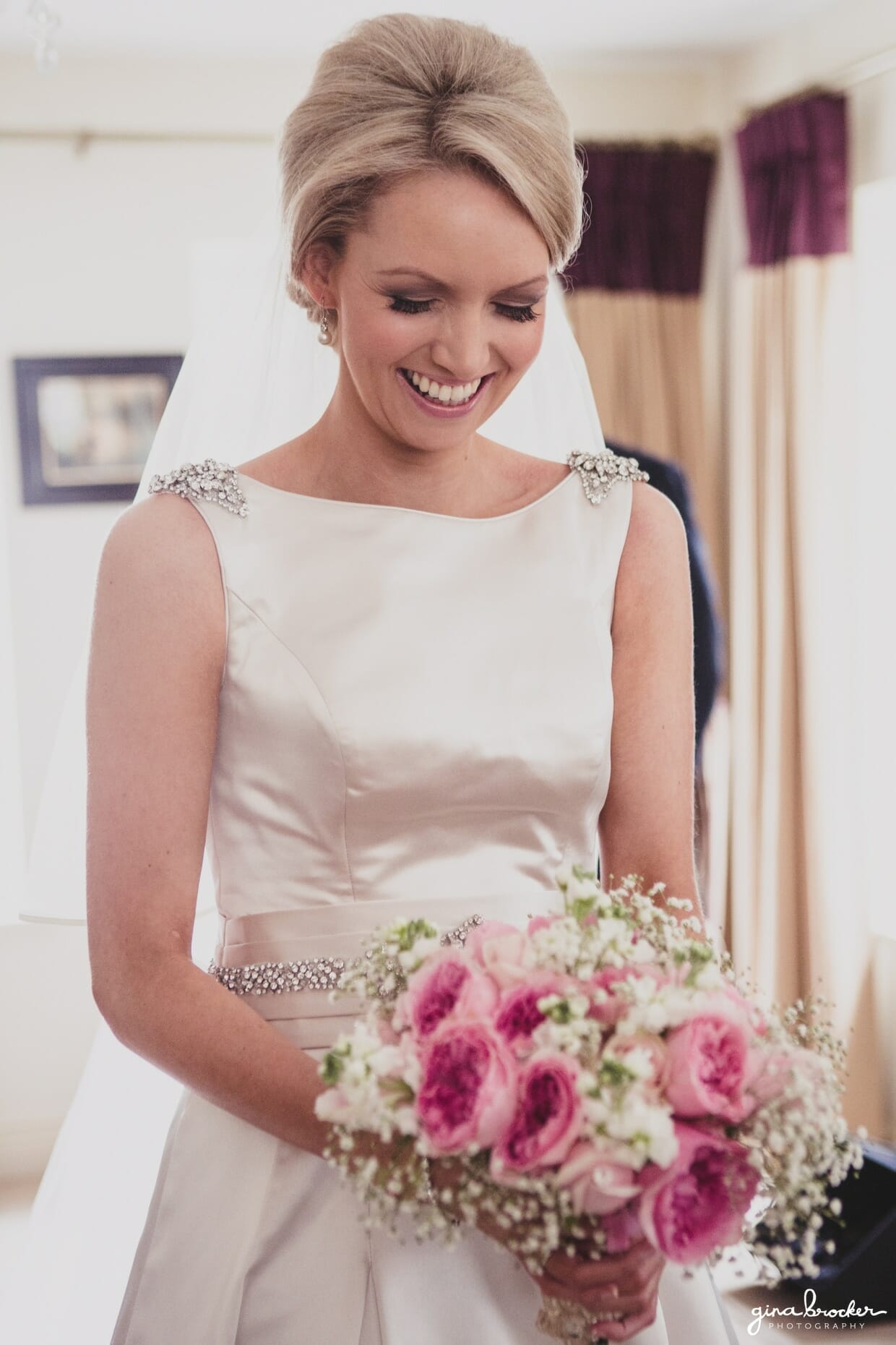 A natural portrait of a bride smiling as she holds her rose bouquet on the morning of her classic garden wedding