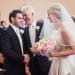 A sweet photograph of a groom shaking the father of the bride's hand as he stares lovingly at his bride during their church ceremony in Boston, Massachusetts
