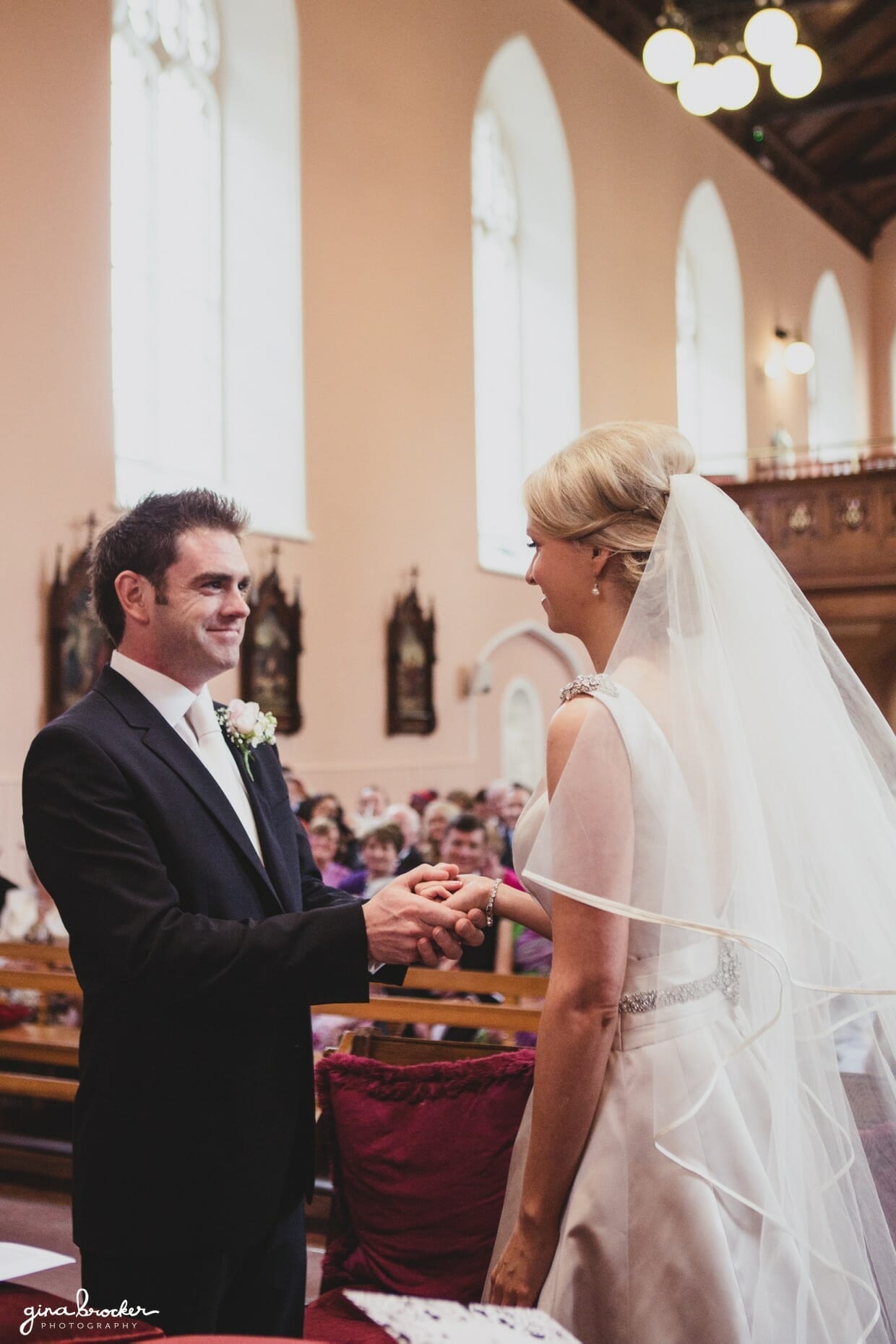 The bride and groom hold hands after exchanging the wedding rings during their religious wedding ceremony