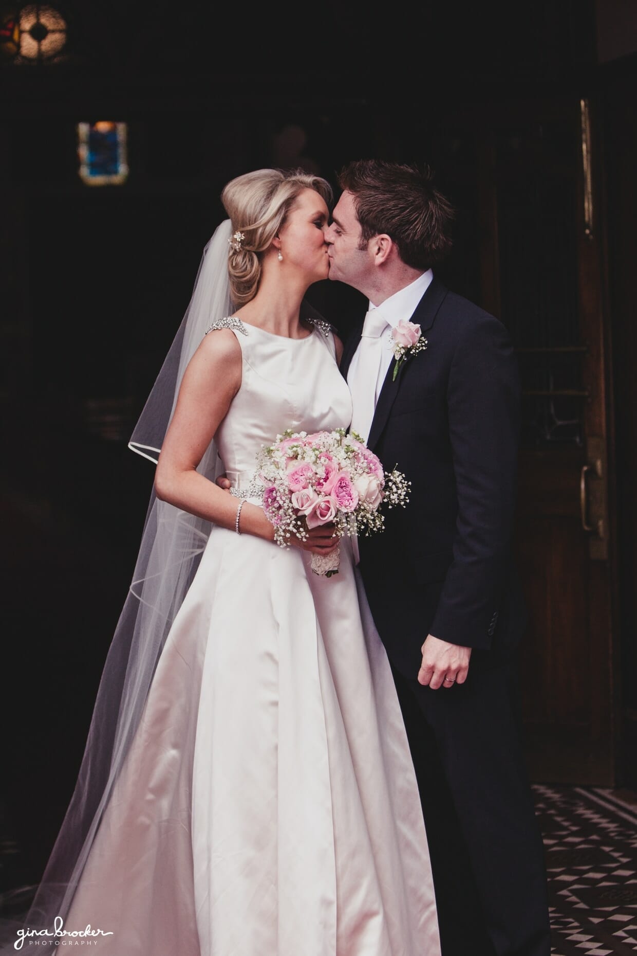 The bride and groom kiss at the entrance of the church just after their intimate religious wedding ceremony