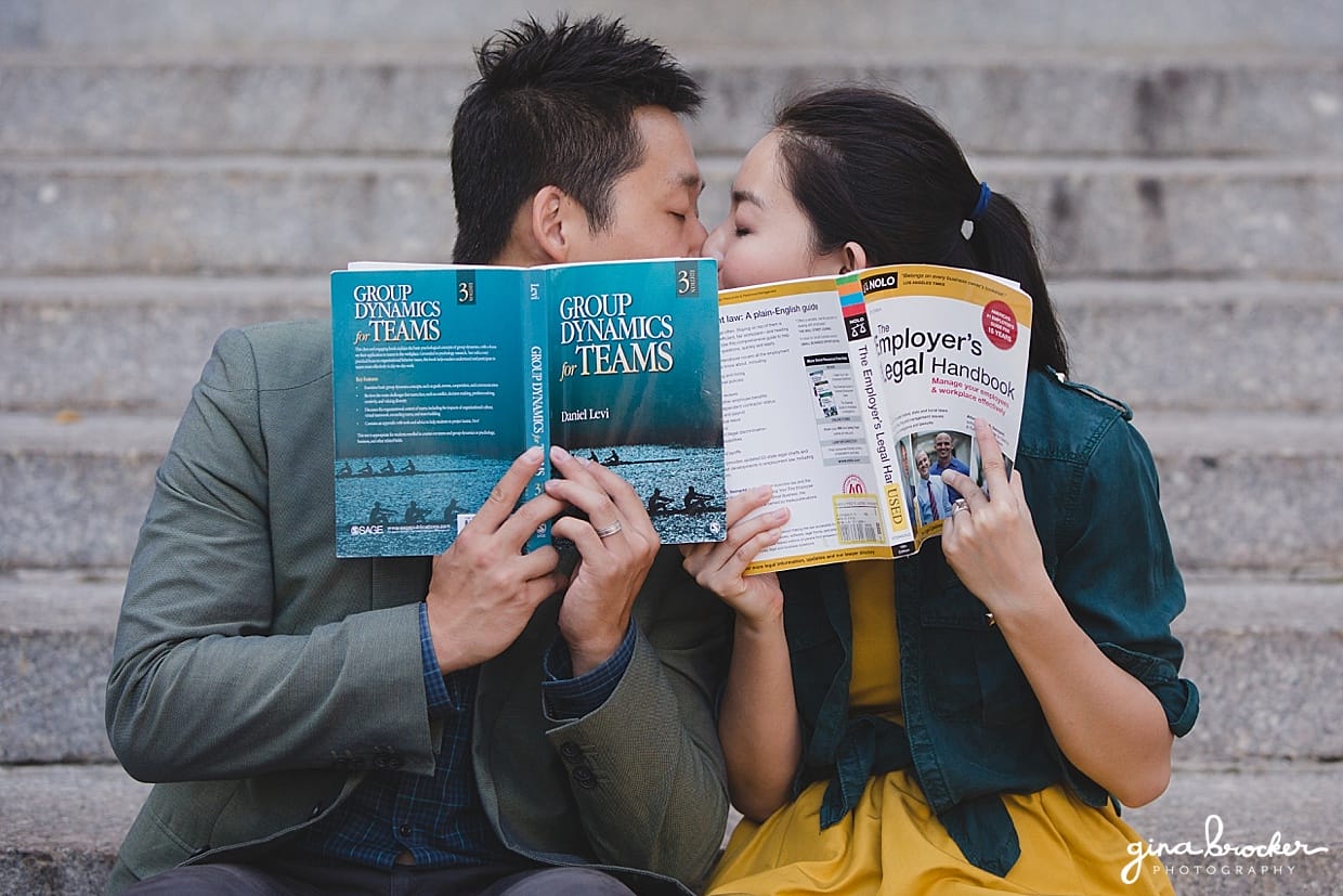 A cute photograph of a couple kissing behind books during their university themed engagement session at Northeastern University in Boston, Massachusetts