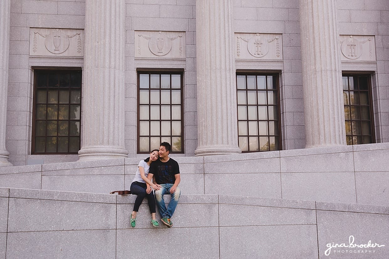 A sweet photograph of couple sitting on a wall during their engagement session at the Boston Museum of Fine Art