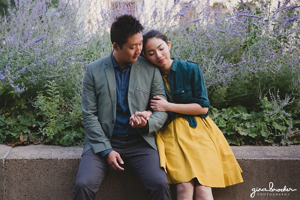 A couple sit together and hold hands amongst lavender during their Christian Science Center Engagement in Boston, Massachusetts