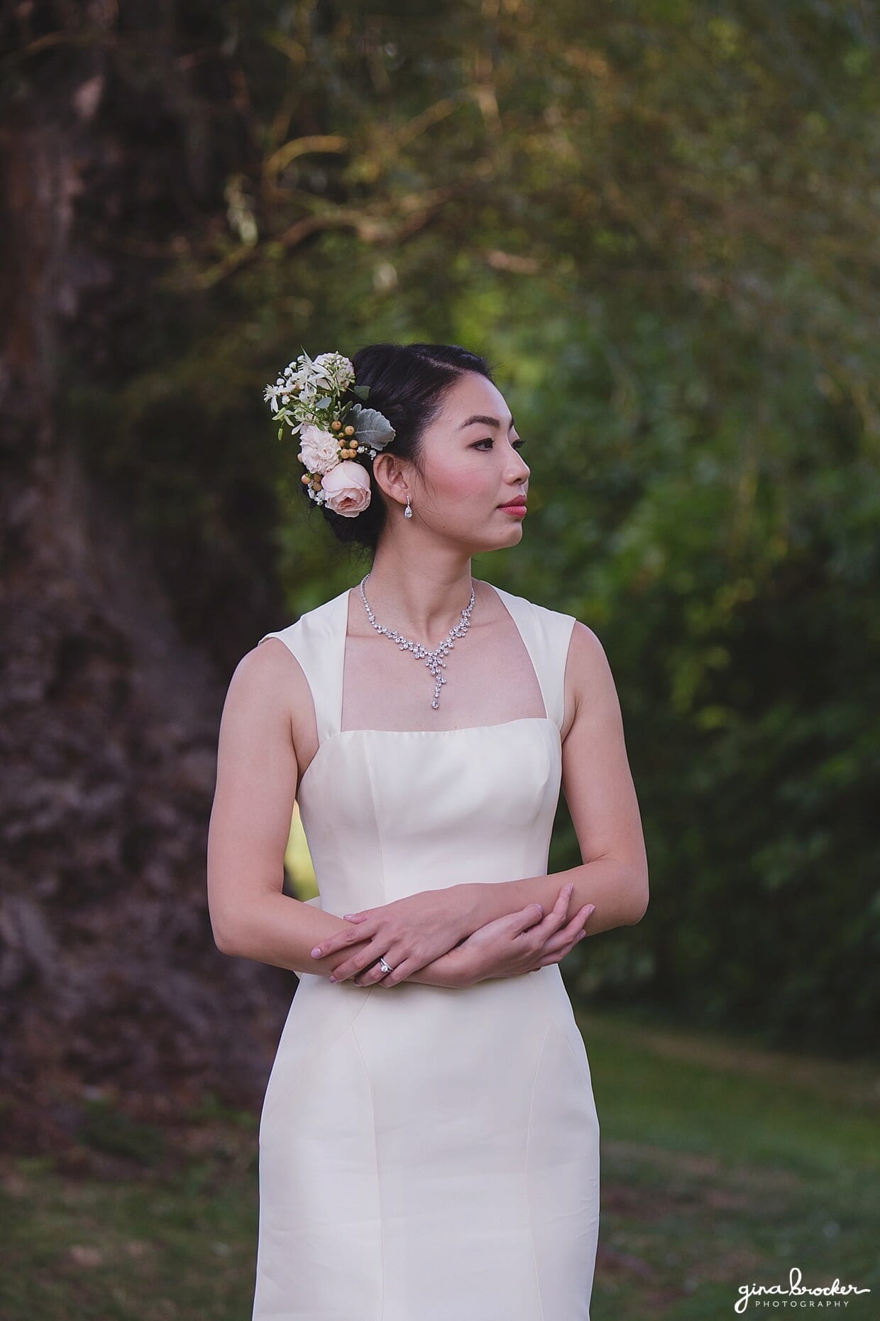 A portrait of a bride in Mill Pond Park wearing a classic Amsale dress and pink floral hairpiece 