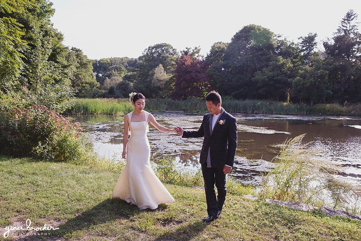 A bride and groom walk hand in hand during their first look at Mill Pond Park, Rockport, Massachusetts