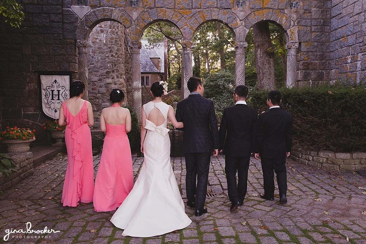 A wedding party wearing pink and black walk away together during a hammond castle wedding in Gloucester, Massachusetts