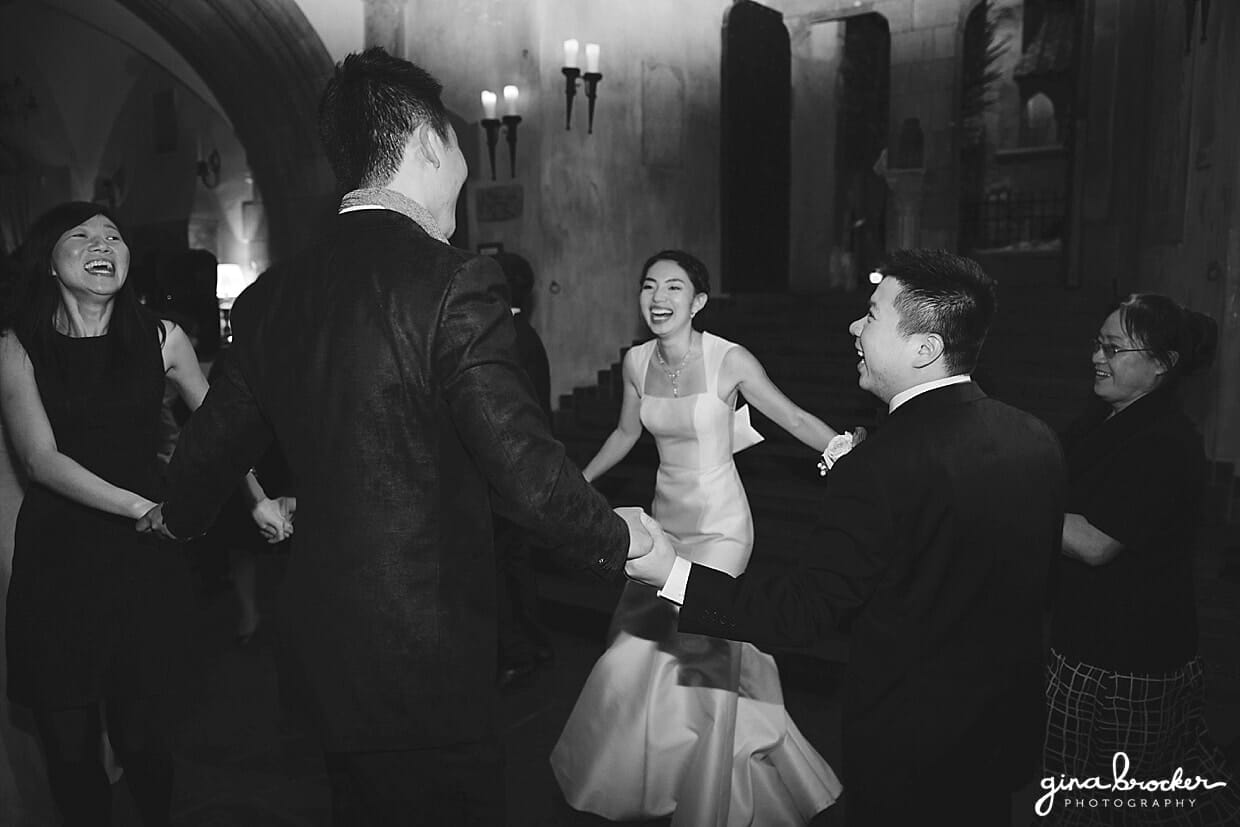 A candid photograph of the bride and groom dancing with friends at their Hammond Castle Wedding in Gloucester, Massachusetts