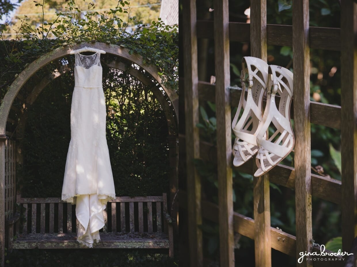 A beautiful photograph of a lace amy kuschel wedding dress and chanel wedding shoes hanging in the garden of a nantucket home on the morning of a westmoor club wedding