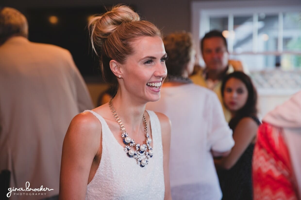 A candid photograph of a bride smiling during her wedding rehearsal dinner at Back Yard BBQ in Nantucket, Massachusetts